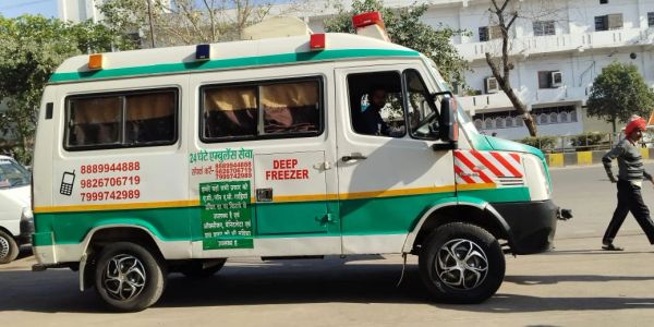 Green and white ambulance labeled 'Deep Freezer' on a city street.