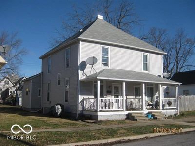 Two-story house with a front porch and satellite dishes on a clear day.