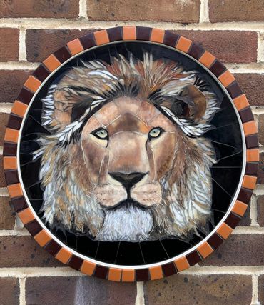 Mosaic lion face art mounted on a brick wall.