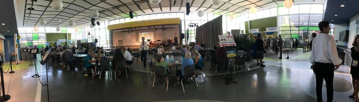 Indoor event with seated attendees and a presenter on stage.