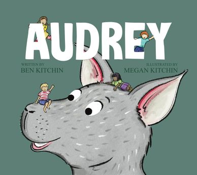 Children playfully interact with a giant gray dog's head on a book cover titled AUDREY.