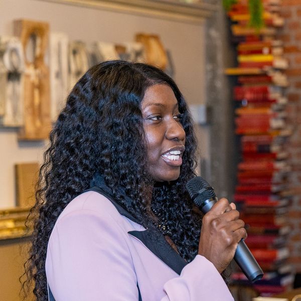 Woman speaking into a microphone at an event.