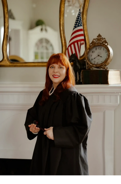 Woman judge in black robe holding a gavel, smiling.