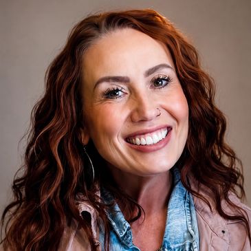 Smiling woman with curly red hair and nose ring.