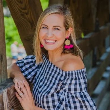 Smiling woman in a checkered off-shoulder top and pink earrings.