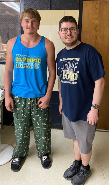 Two young men standing indoors, smiling at the camera.