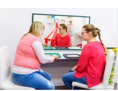 Two women using AAC device during speech therapy session