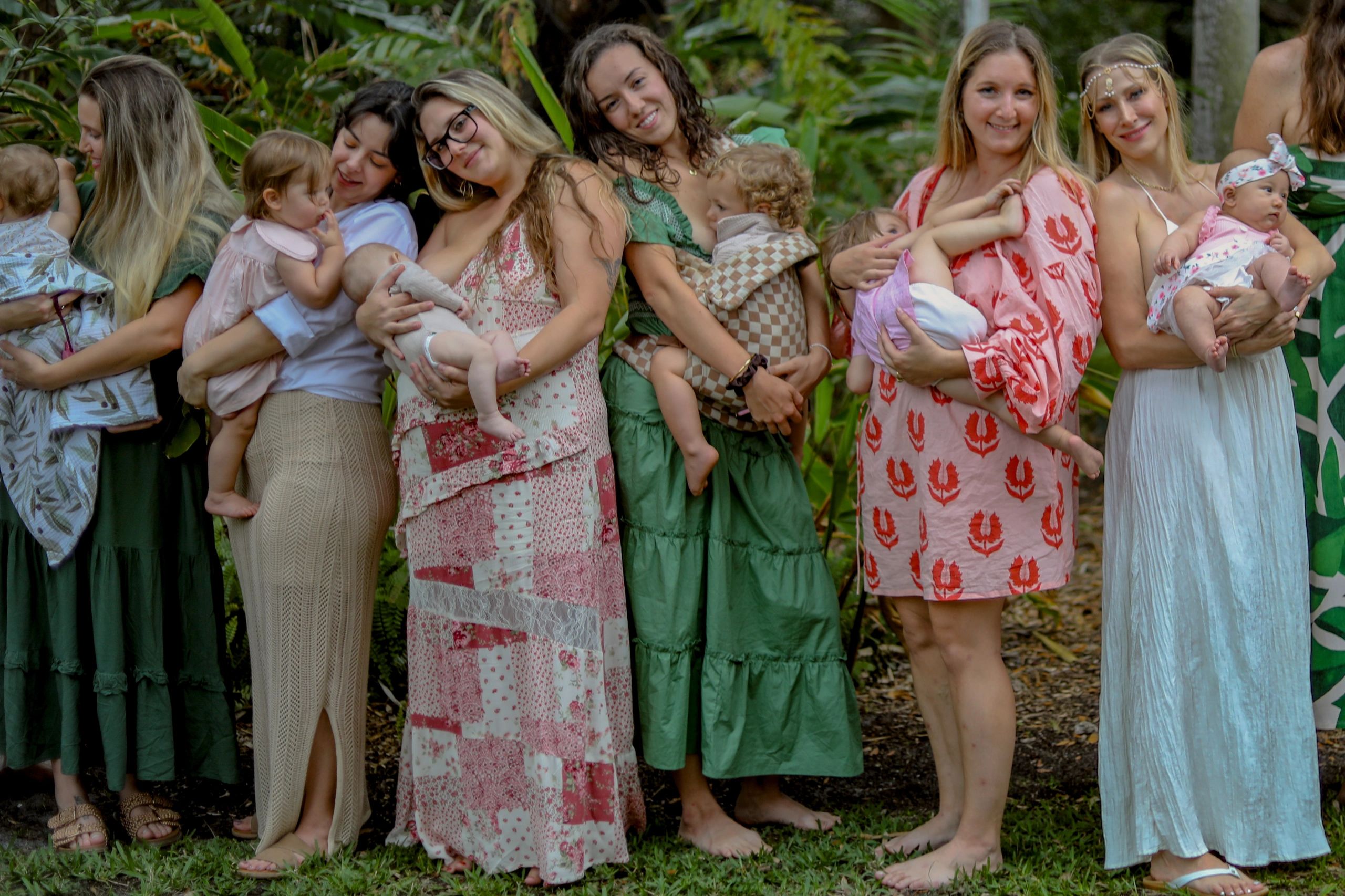 Group of women outdoors holding their babies, smiling warmly.