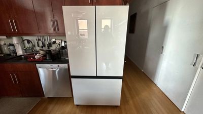 Modern white refrigerator in a kitchen with wooden cabinets.