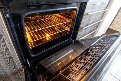 Open oven with heating elements glowing inside in a modern kitchen.