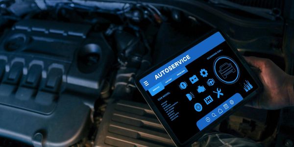 Tablet showing autoservice diagnostics near car engine.
