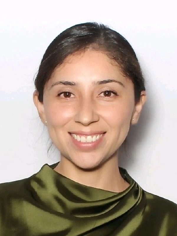 Smiling woman with dark hair and an olive green satin top.