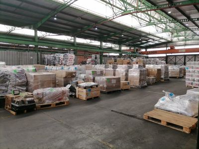 Warehouse with pallets of goods wrapped in plastic and stacked inside a large industrial building.