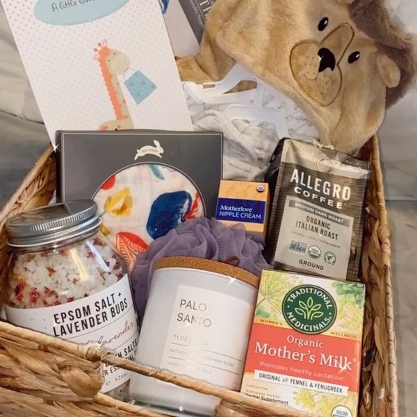 A cozy gift basket with bath salts, coffee, candle, and baby essentials.