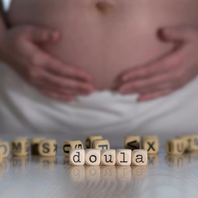 Wooden blocks spelling 'doula' with a pregnant belly in the background.