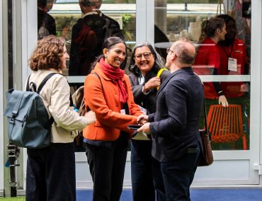 Four people engaged in friendly conversation outdoors.