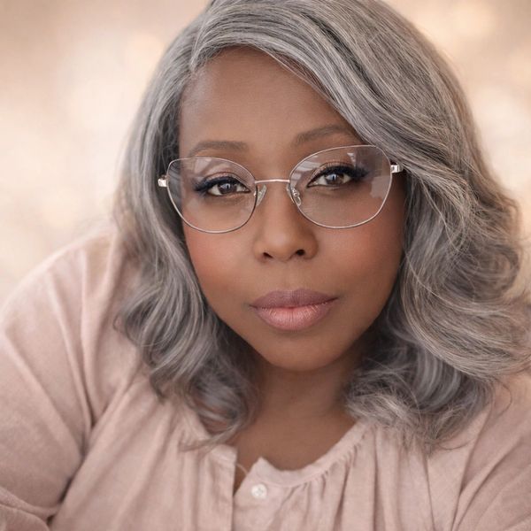Portrait of a confident woman with gray hair and glasses.