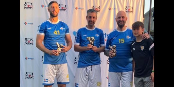 Three male athletes holding trophies with a young boy beside them.