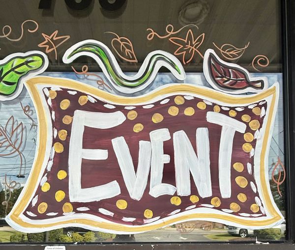 Hand-painted window sign with "EVENT" in bold letters and fall leaf decorations.