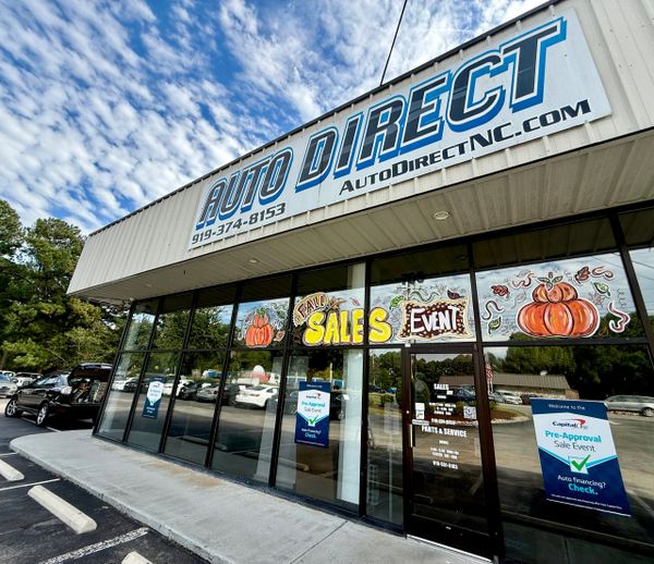 Auto Direct storefront advertising a fall sales event with pumpkin decorations.