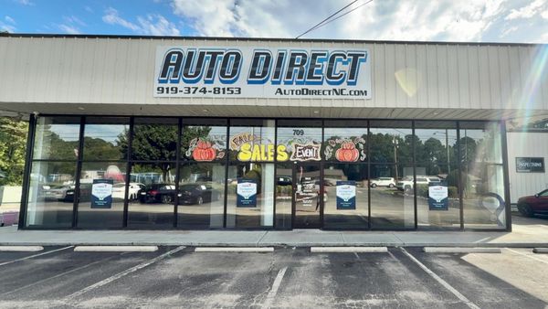 Auto Direct storefront with Fall Sales Event decorations on windows.