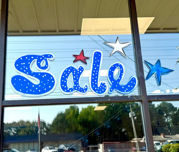 Colorful window painting advertising a sale with stars.