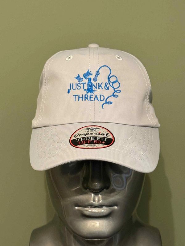 White baseball cap with blue embroidery and UPF 50+ sticker on a mannequin head.