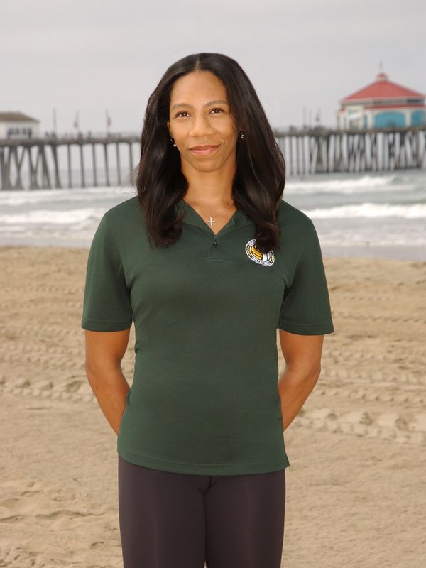 Woman standing on the beach with pier in background.