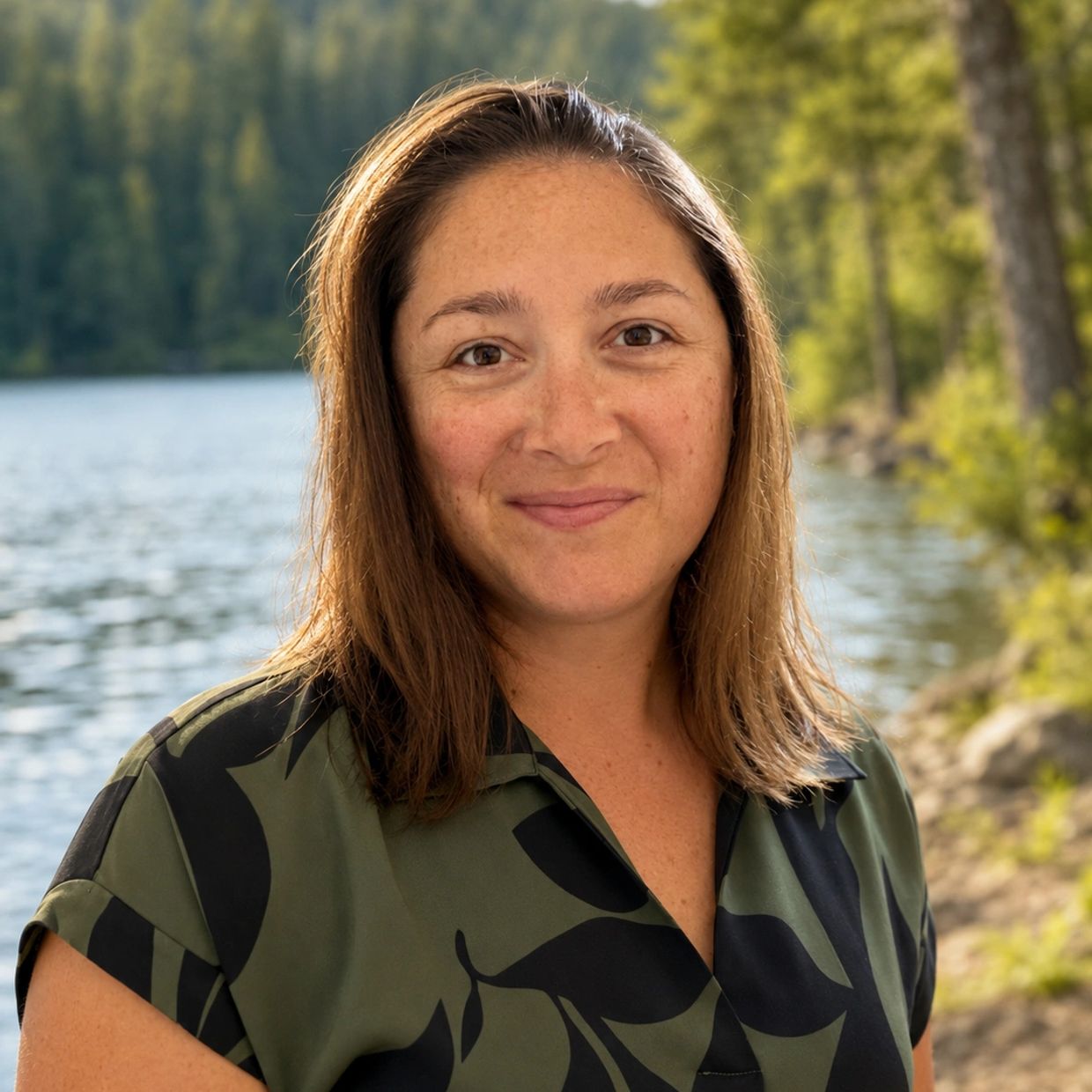A woman smiling near a lake.