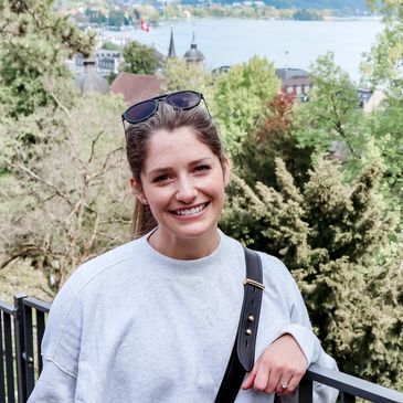 smiling woman in nature with trees, mountains, and a lake