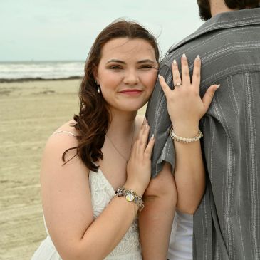 Woman embraces a man on the beach, smiling.