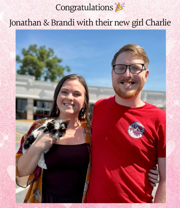 Jonathan and Brandi smiling with their new puppy Charlie outside.