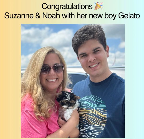 Suzanne and Noah smile, holding their new puppy Gelato outdoors.