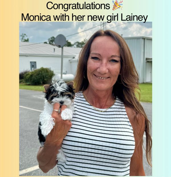 Monica happily holding her new puppy Lainey outdoors.