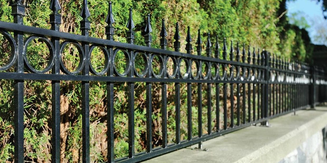 A long black metal fence with pointed finials along a stone base.