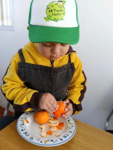 Niño con gorra pelando una mandarina.