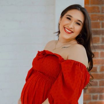 Smiling woman in a red off-shoulder dress.