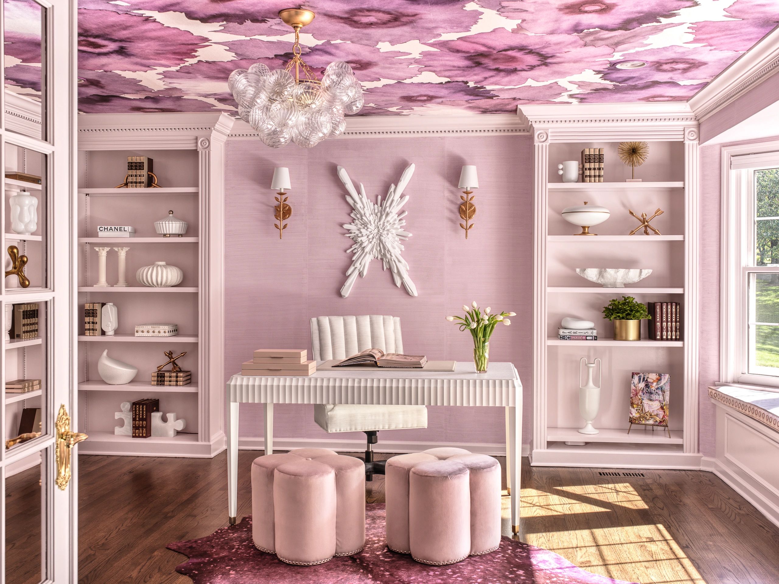 Home office with pink floral wallpaper on the ceiling. Bubble chandelier, white, marble desk.