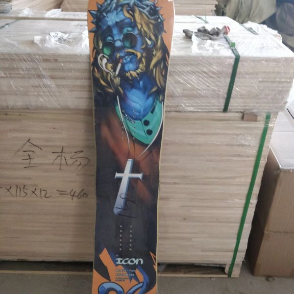 Snowboard with artistic blue face design leaning against wood.