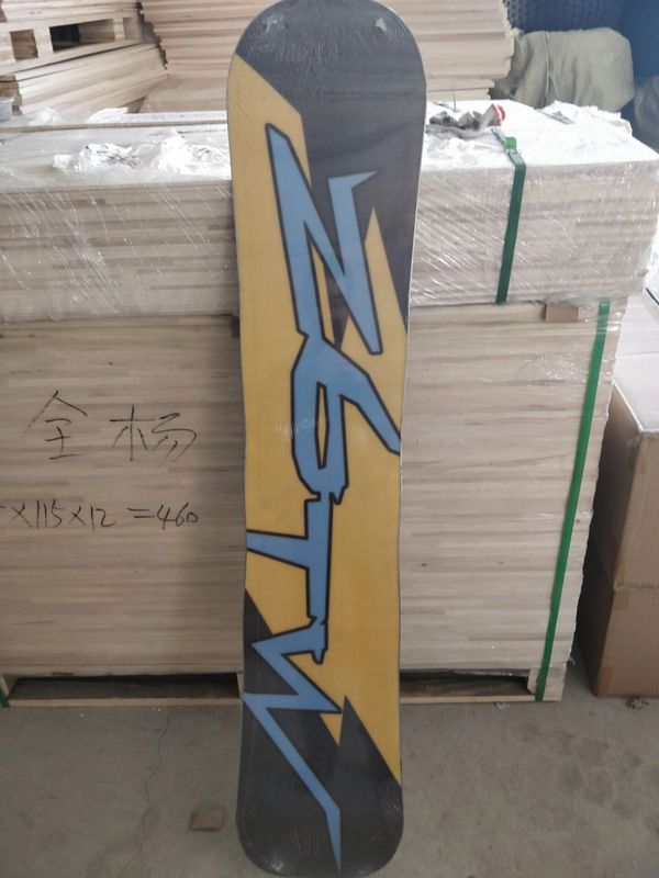 A snowboard with bold blue and yellow geometric design leaning against stacked wood panels.