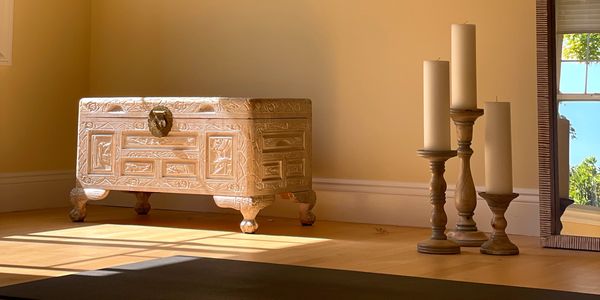 Ornate wooden chest and candles in a sunlit room.