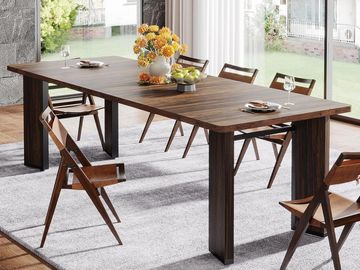 Dark brown slim dining table and folding chairs of wood with yellow flowers in a vase and a glass ba
