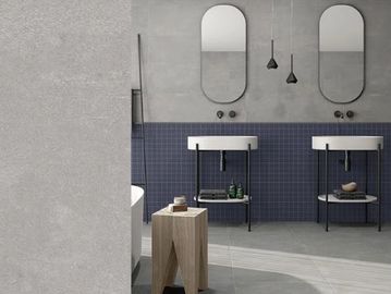 Grey and navy bathroom floor and wall tiles with two floor-standing white washbasins