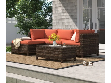 Orange outdoor rattan corner set on a patio with a rug and a coffee table