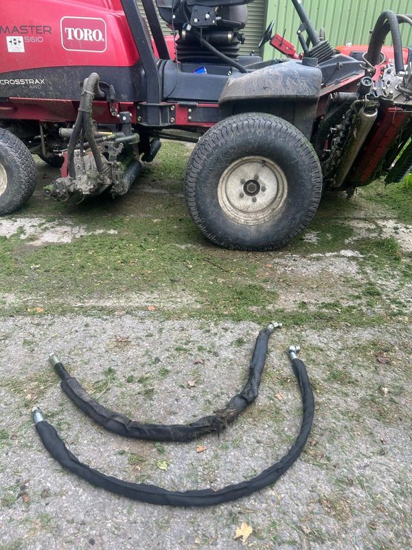 Two hoses on the ground beside a Toro mower.
