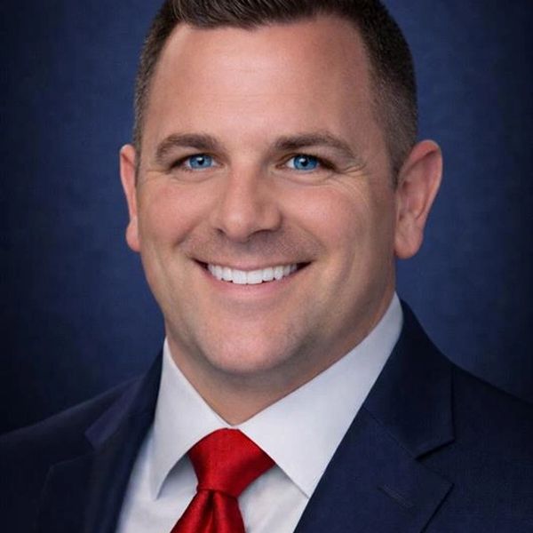 Smiling man in a suit with a red tie.
