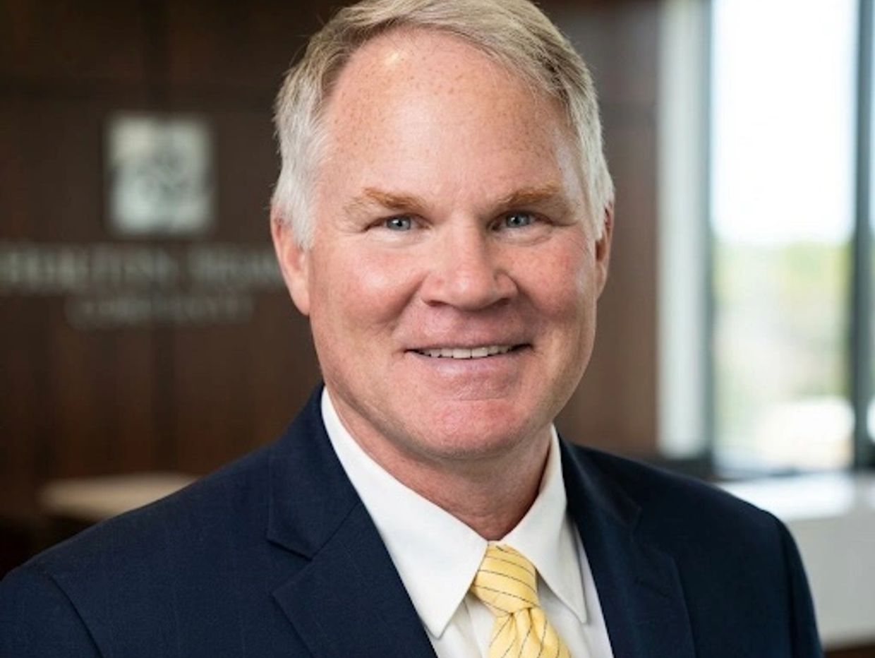 Smiling middle-aged man in suit with yellow tie.