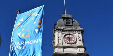 A clock tower with a blue Harmony Fest flag.