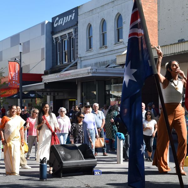Woman dancing with Australian flag and crowd watching.