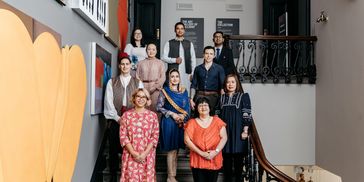 Group of ten diverse people posing on staircase indoors.